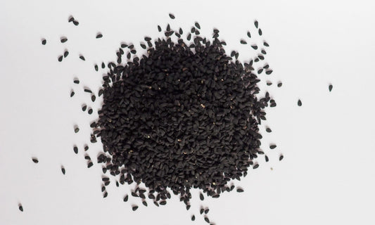 Graines de nigelle entières présentées en tas sur fond clair