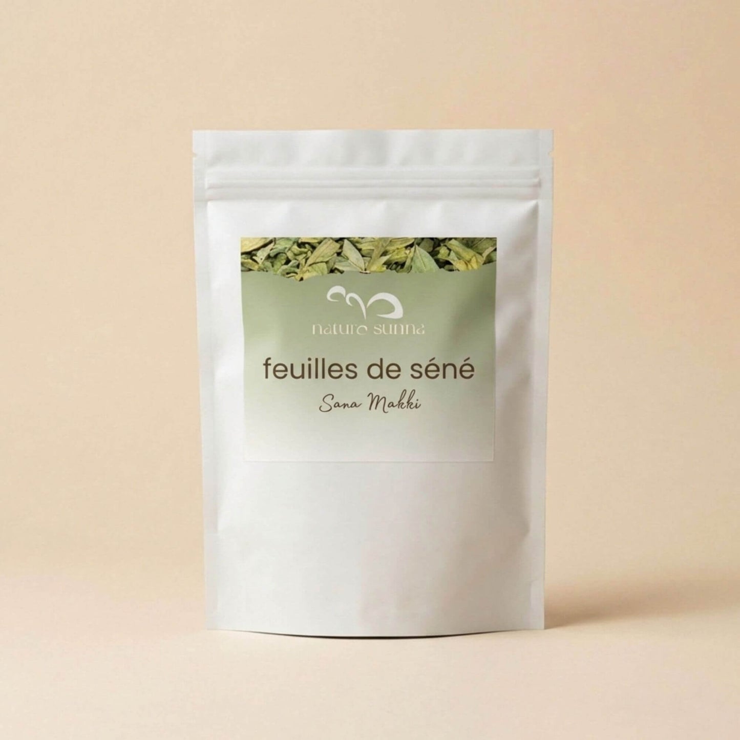Feuilles de séné Sana Makki Naturo Sunna, plante sèche en vrac, présentée en sachet refermable sur fond beige naturel.