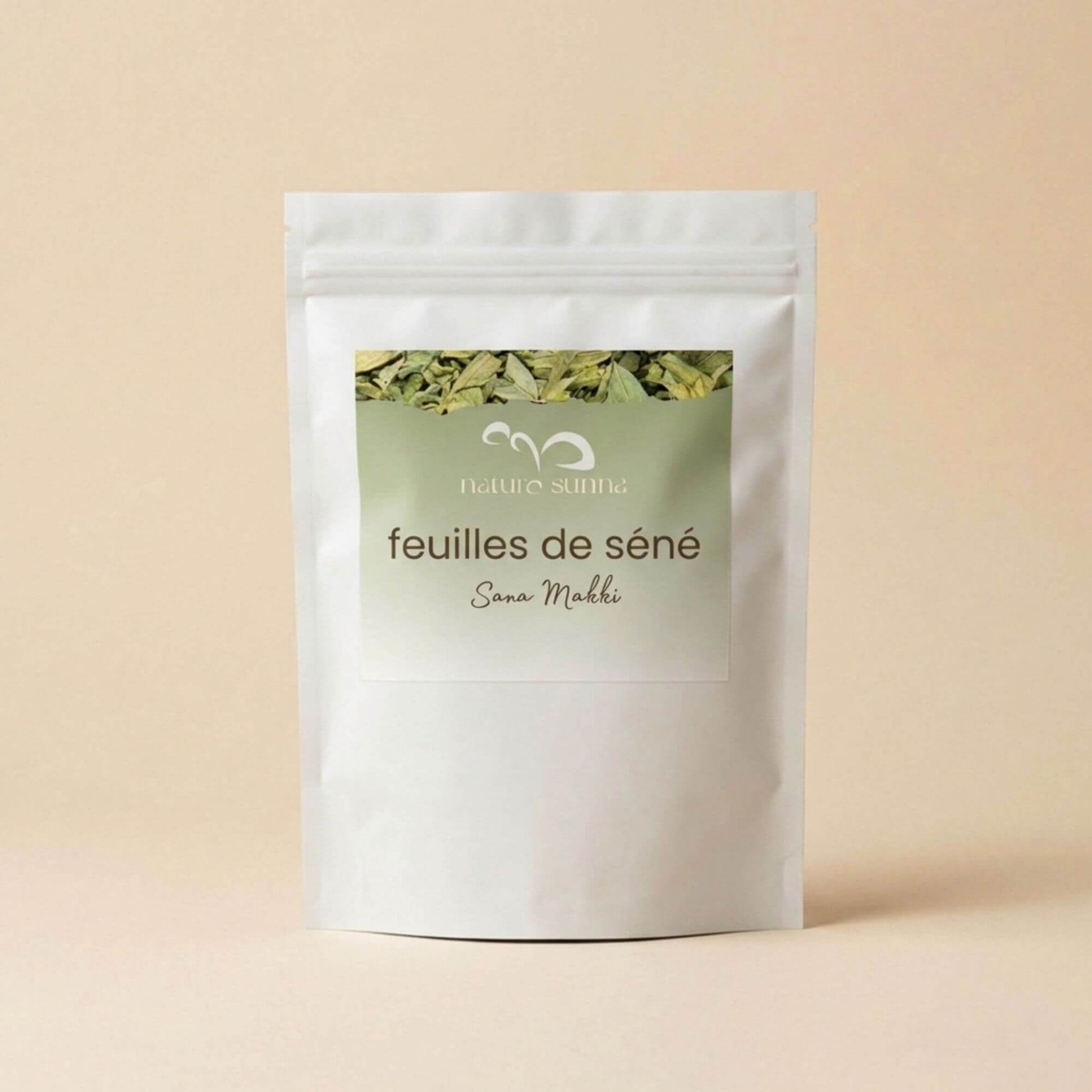 Feuilles de séné Sana Makki Naturo Sunna, plante sèche en vrac, présentée en sachet refermable sur fond beige naturel.