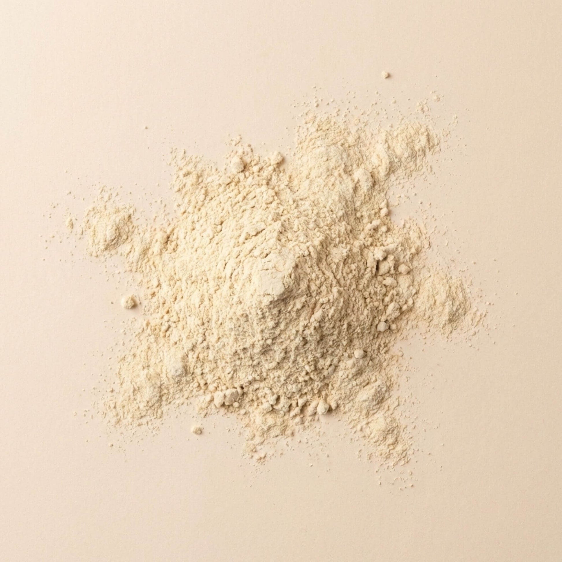 Pollen de palmier en poudre fine, présenté en tas sur fond beige neutre, matière brute non transformée.