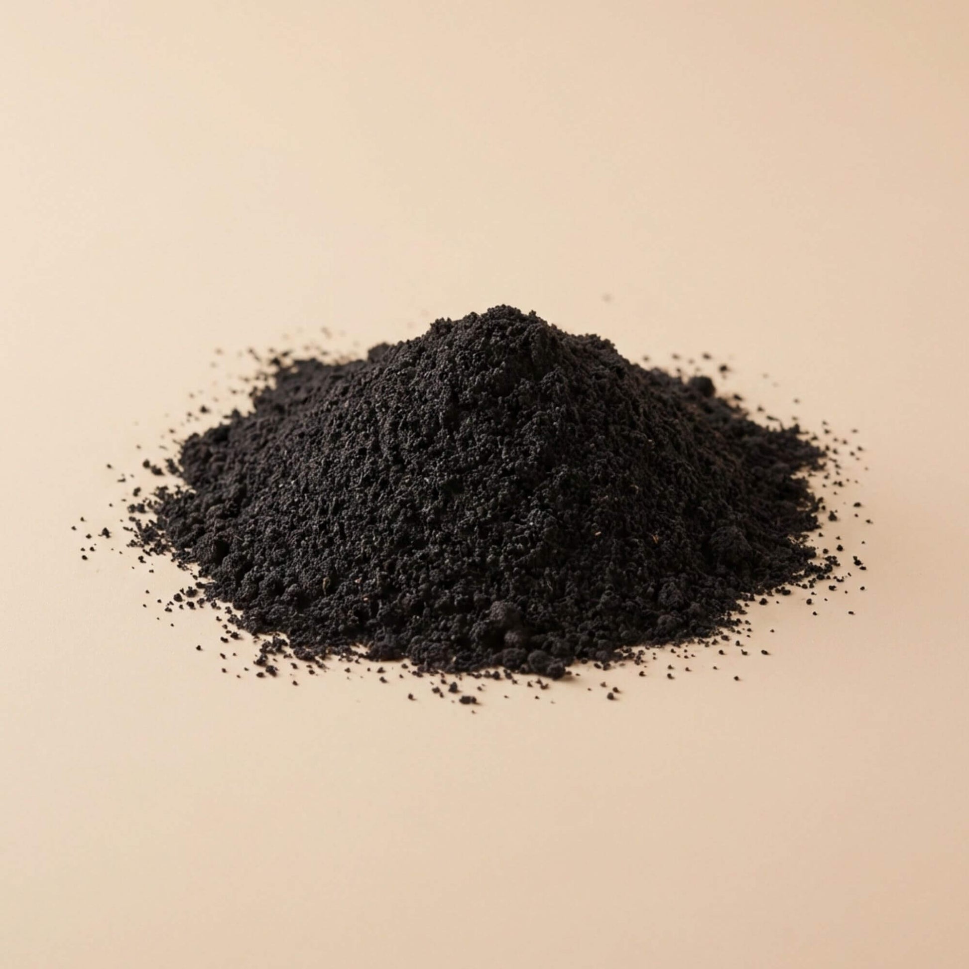 Poudre de nigelle Habba Sawda noire, présentée en tas sur fond beige, issue de graines finement moulues.