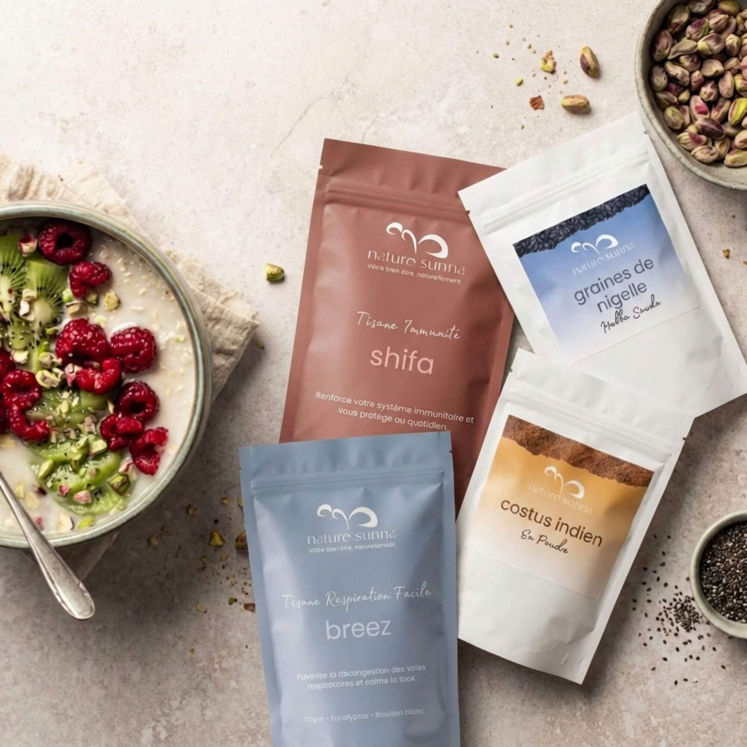 Sélection de tisanes et remèdes naturels Naturo Sunna : tisane Shifa, tisane Breez, graines de nigelle et costus indien en poudre, présentés sur fond clair avec ingrédients bruts